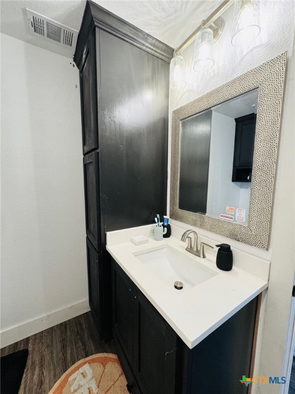 bathroom with wood finished floors, vanity, baseboards, and visible vents