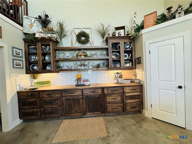 bar with tasteful backsplash, baseboards, and concrete flooring