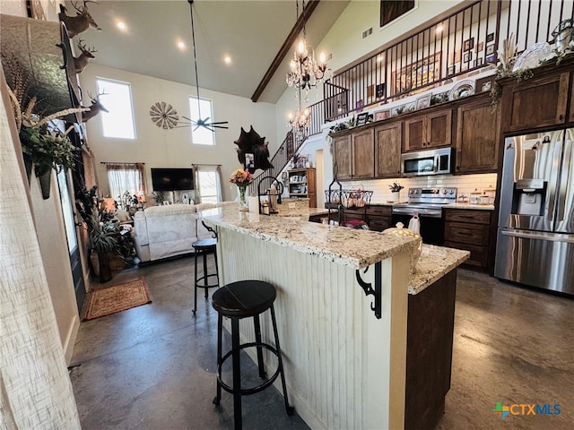 kitchen with open floor plan, concrete flooring, a towering ceiling, and stainless steel appliances