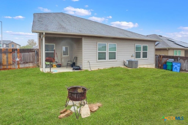 rear view of property with a lawn, a patio area, a fire pit, and central AC unit