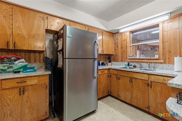 134 Daisy Ln, Whitney, TX 76692 - kitchen with freestanding refrigerator, a sink, light countertops, a textured ceiling, and brown cabinets