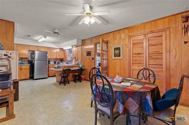 134 Daisy Ln, Whitney, TX 76692 - dining space with wood walls, a textured ceiling, ceiling fan, and light floors