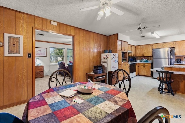 134 Daisy Ln, Whitney, TX 76692 - dining area featuring wooden walls, ceiling fan, and a textured ceiling