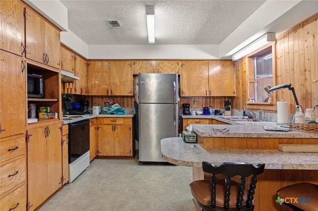 134 Daisy Ln, Whitney, TX 76692 - kitchen with freestanding refrigerator, range with electric cooktop, black microwave, under cabinet range hood, and a sink