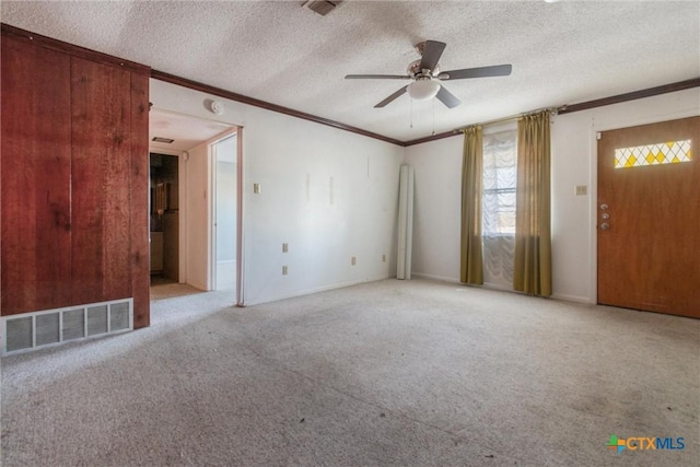 carpeted empty room featuring ceiling fan, a textured ceiling, and crown molding