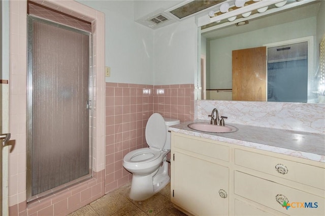 bathroom featuring toilet, a shower with shower door, tile patterned flooring, tile walls, and vanity