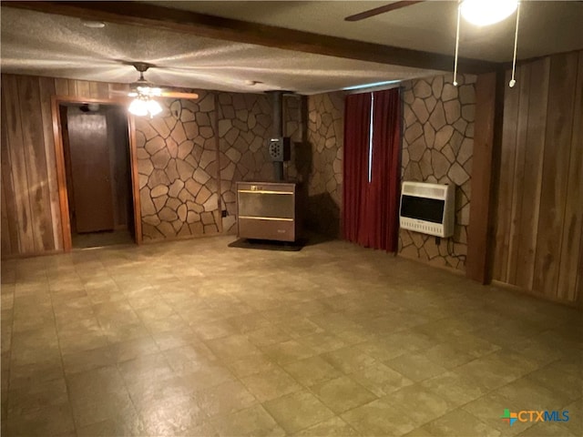 basement with wood walls, ceiling fan, and heating unit