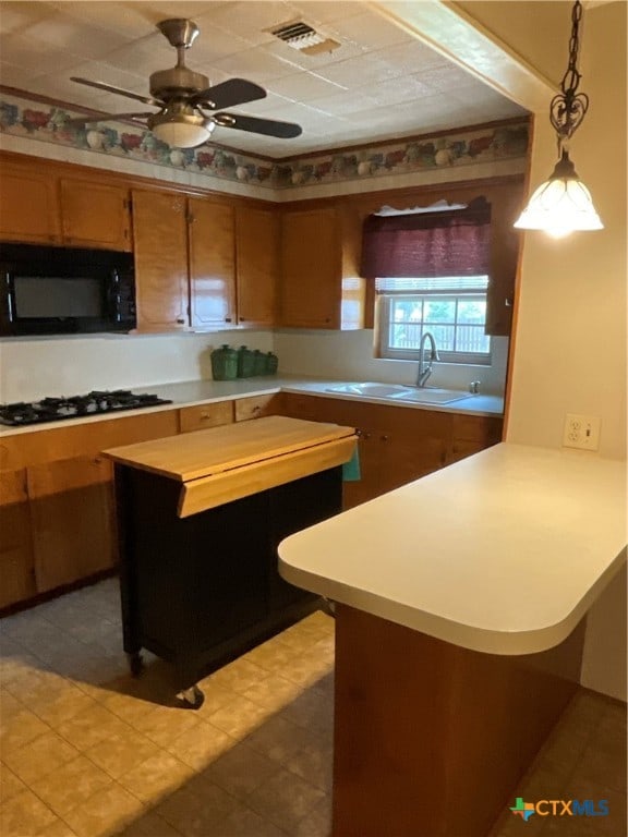 kitchen with white gas cooktop, tile patterned floors, hanging light fixtures, sink, and ceiling fan