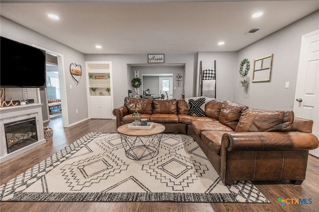 living room featuring hardwood / wood-style flooring, plenty of natural light, and built in shelves