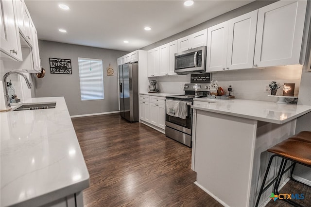 kitchen with a breakfast bar, appliances with stainless steel finishes, white cabinetry, and sink