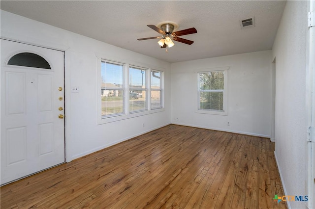 empty room featuring visible vents, baseboards, a ceiling fan, and hardwood / wood-style floors