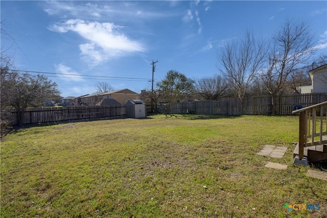 view of yard with a storage shed, a fenced backyard, and an outbuilding