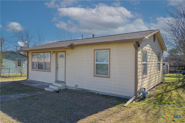 view of front of house with entry steps, a front yard, and fence