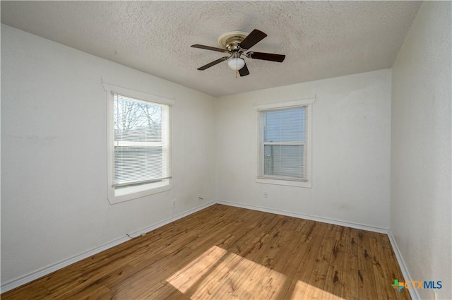 empty room featuring ceiling fan, baseboards, a textured ceiling, and wood finished floors