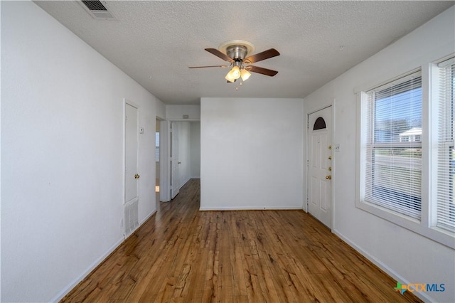 interior space featuring visible vents, baseboards, wood finished floors, a textured ceiling, and a ceiling fan