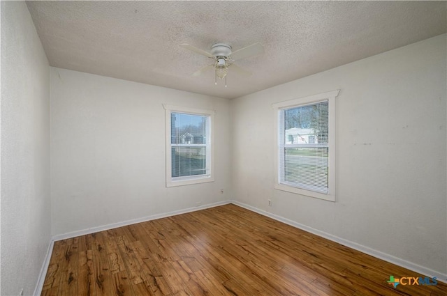 spare room featuring hardwood / wood-style floors, a ceiling fan, baseboards, and a textured ceiling