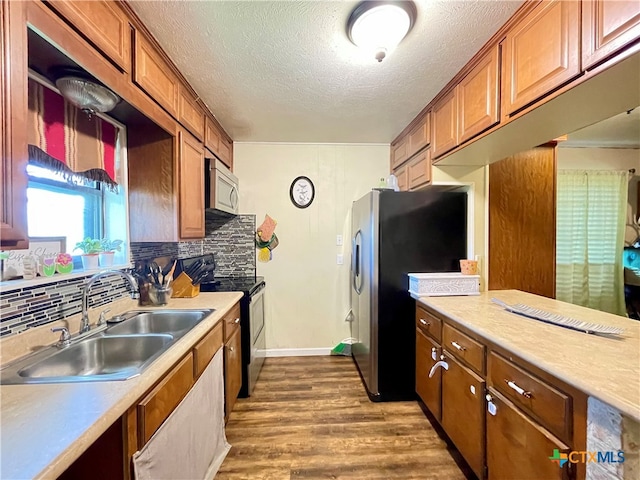 kitchen with backsplash, appliances with stainless steel finishes, a textured ceiling, dark hardwood / wood-style flooring, and sink