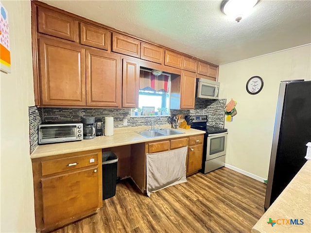 kitchen with stainless steel appliances, dark wood-type flooring, sink, and tasteful backsplash