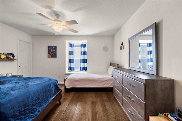 bedroom with a textured ceiling, ceiling fan, and dark wood-style flooring