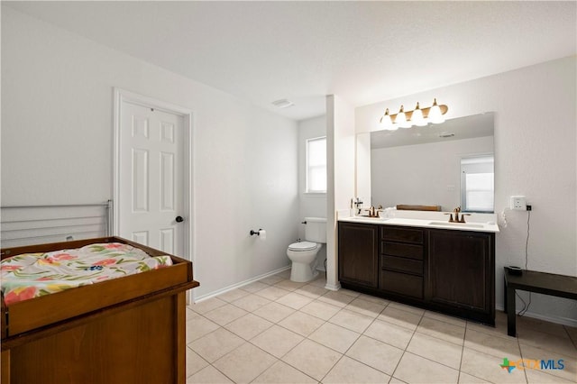 bathroom with baseboards, double vanity, a sink, tile patterned floors, and toilet