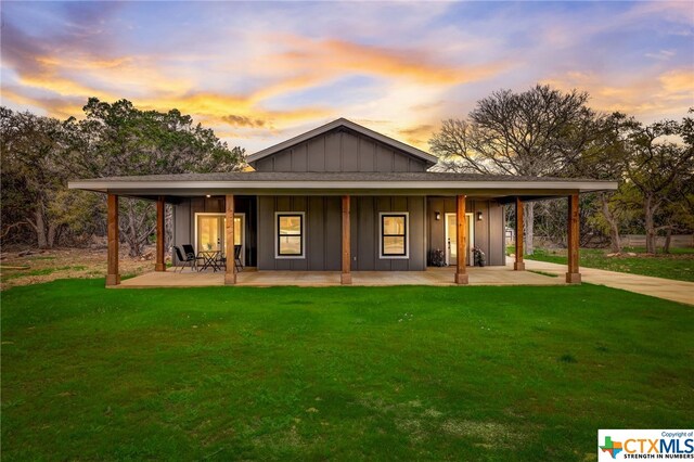 back house at dusk with a yard and a patio area