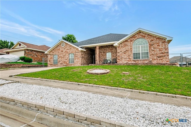 view of front of property featuring roof with shingles, a front yard, and brick siding