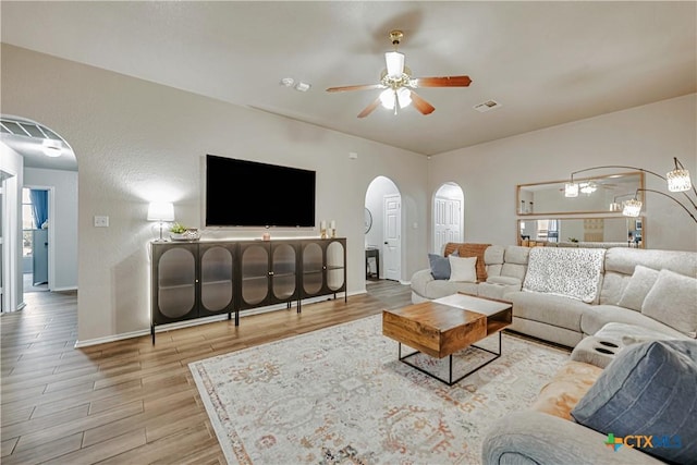 living room with ceiling fan, visible vents, arched walkways, wood finished floors, and baseboards
