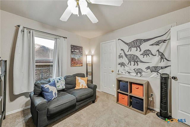 living area featuring baseboards, a ceiling fan, and carpet