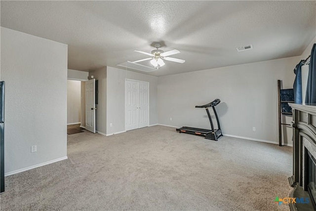 workout area featuring carpet floors, a textured ceiling, a ceiling fan, baseboards, and visible vents
