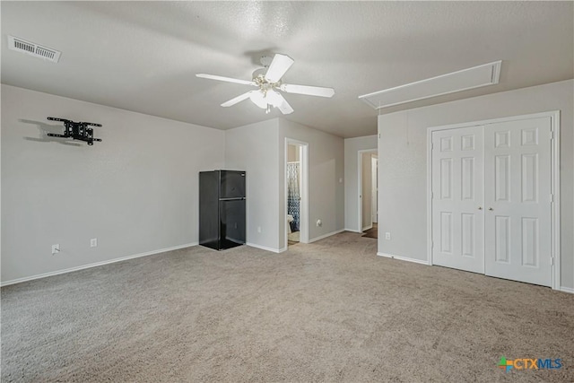 unfurnished bedroom with ceiling fan, attic access, visible vents, carpet floors, and baseboards