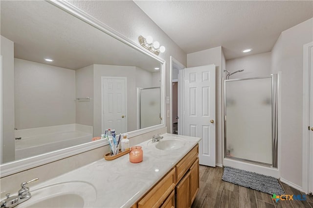 bathroom featuring a sink, double vanity, a stall shower, and wood finished floors