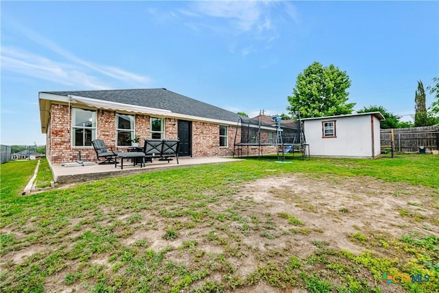 back of property featuring a lawn, brick siding, a patio area, and a trampoline