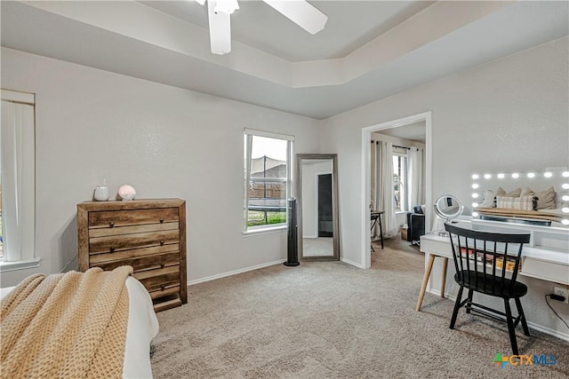 carpeted bedroom featuring baseboards, a tray ceiling, and multiple windows