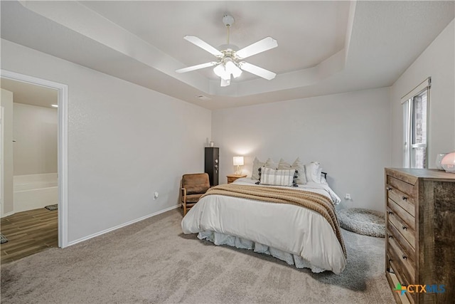 carpeted bedroom with baseboards, ceiling fan, and a tray ceiling