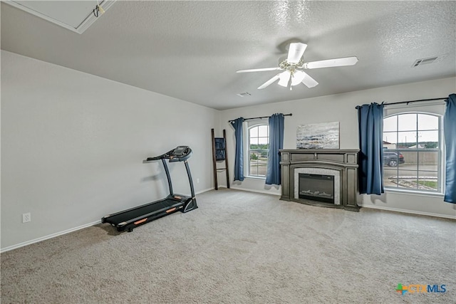 workout room with a textured ceiling, ceiling fan, visible vents, and baseboards