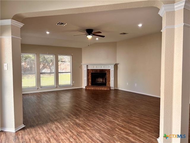 unfurnished living room with a fireplace, ceiling fan, dark hardwood / wood-style flooring, and decorative columns