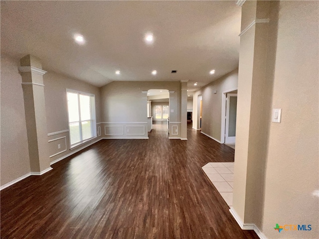 unfurnished living room with dark wood-type flooring, vaulted ceiling, and ornate columns