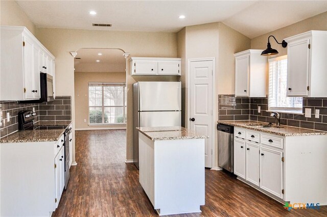 kitchen with dark hardwood / wood-style flooring, a center island, white cabinets, dark stone countertops, and stainless steel fridge