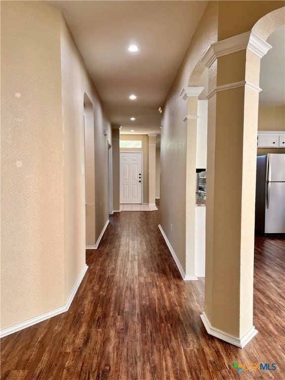 corridor featuring dark wood-type flooring and ornate columns