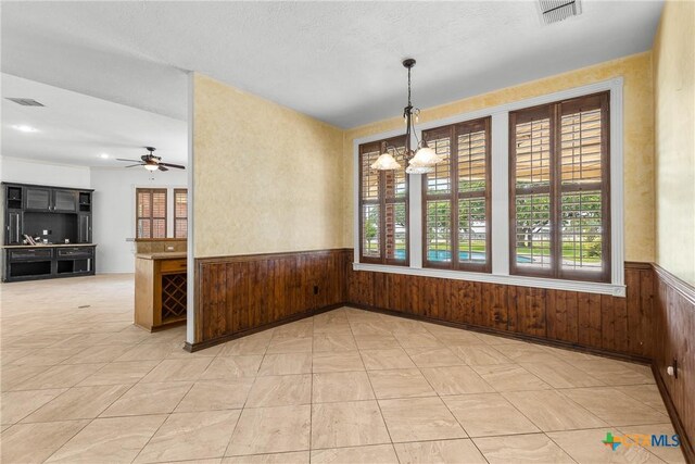 803 S Converse St, Flatonia, TX 78941 - unfurnished dining area with plenty of natural light, a wainscoted wall, a chandelier, wooden walls, and a ceiling fan