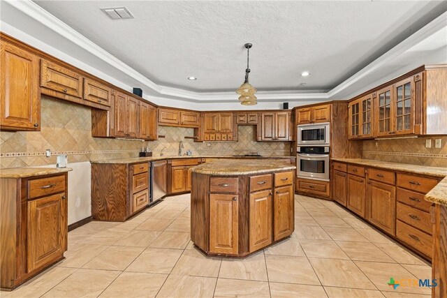 803 S Converse St, Flatonia, TX 78941 - kitchen featuring stainless steel appliances, a tray ceiling, brown cabinetry, tasteful backsplash, and crown molding