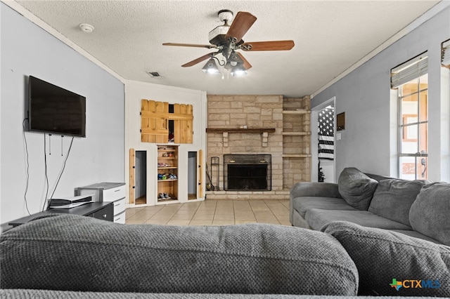 614 Cedar Dr, Copperas Cove, TX 76522 - living room with tile patterned floors, ceiling fan, a textured ceiling, ornamental molding, and a stone fireplace
