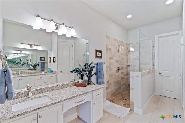 bathroom featuring vanity, tile patterned floors, and tiled shower