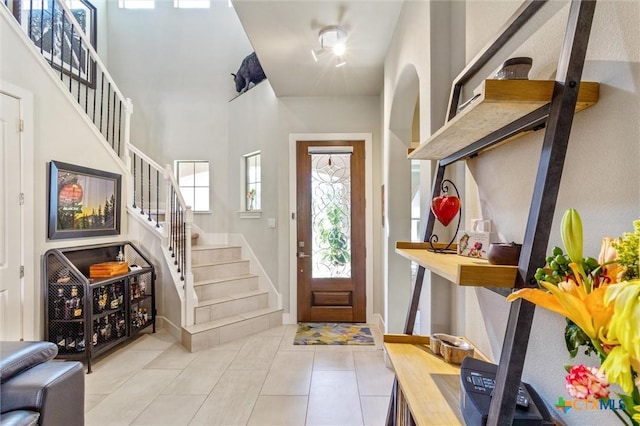 foyer entrance with light tile patterned flooring and a towering ceiling