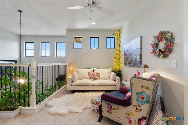 living area featuring ceiling fan, plenty of natural light, and carpet