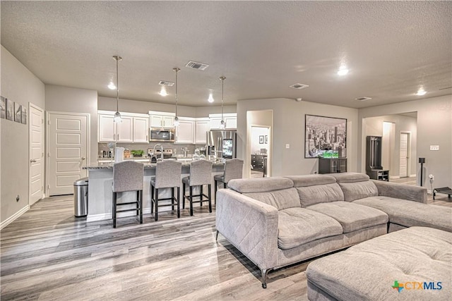 7808 Mcculloch Rd, Temple, TX 76502 - living room featuring light wood-style flooring, baseboards, a textured ceiling, and recessed lighting