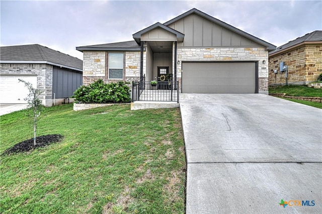 7808 Mcculloch Rd, Temple, TX 76502 - view of front of property with board and batten siding, a front lawn, driveway, an attached garage, and stone siding