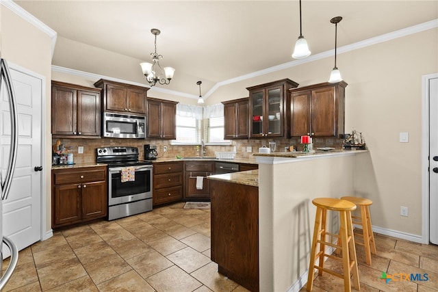 kitchen featuring tasteful backsplash, kitchen peninsula, decorative light fixtures, a kitchen bar, and appliances with stainless steel finishes