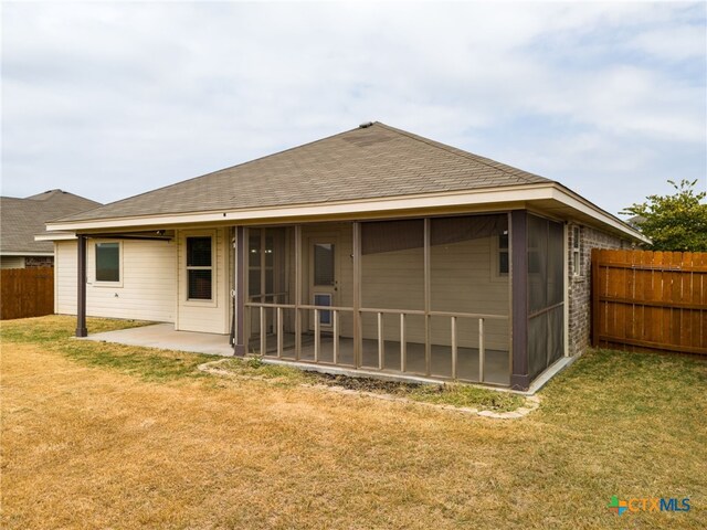 back of property featuring a lawn, a sunroom, and a patio