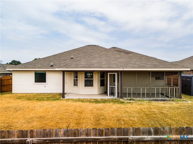 rear view of property featuring a yard, a patio, and a sunroom